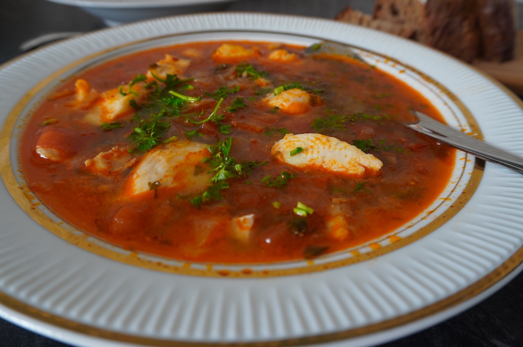 Moroccan fish soup in serving plate with pieces of fish garnished with parsley close view