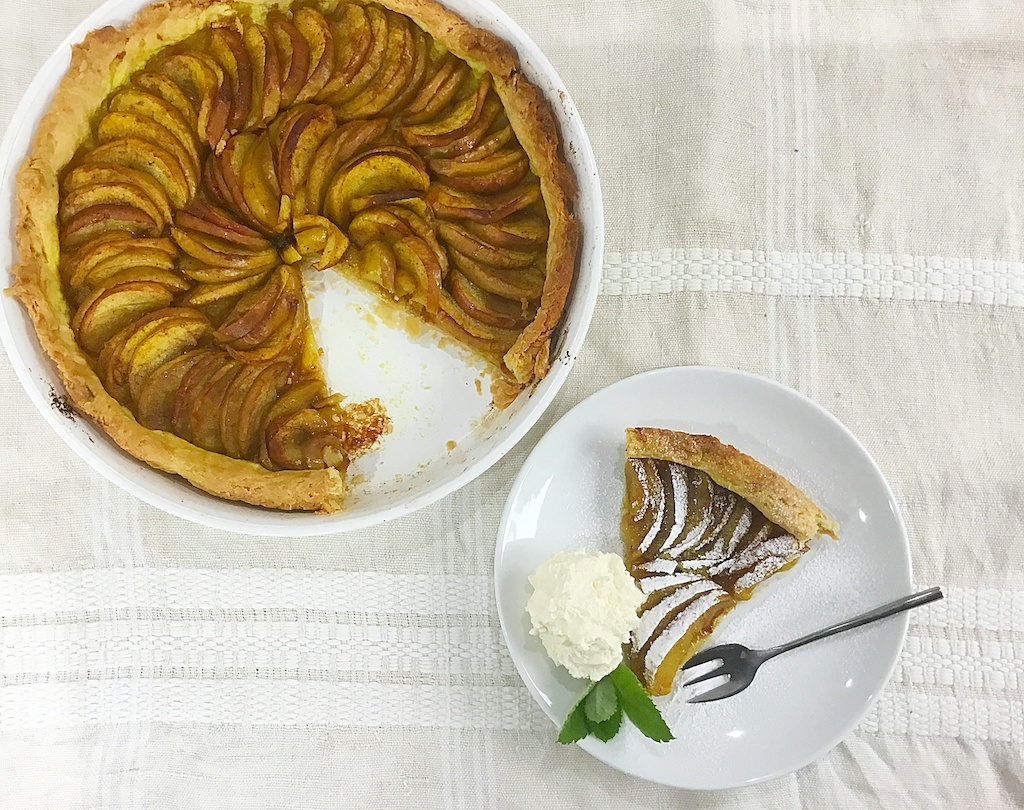 apple tart with a piece taken out onto a serving plate