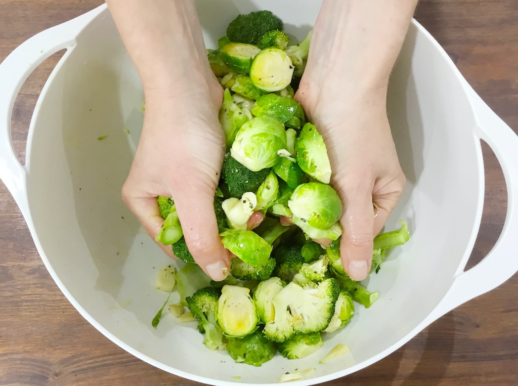 Brussels sprouts and broccoli being rubbed with spices
