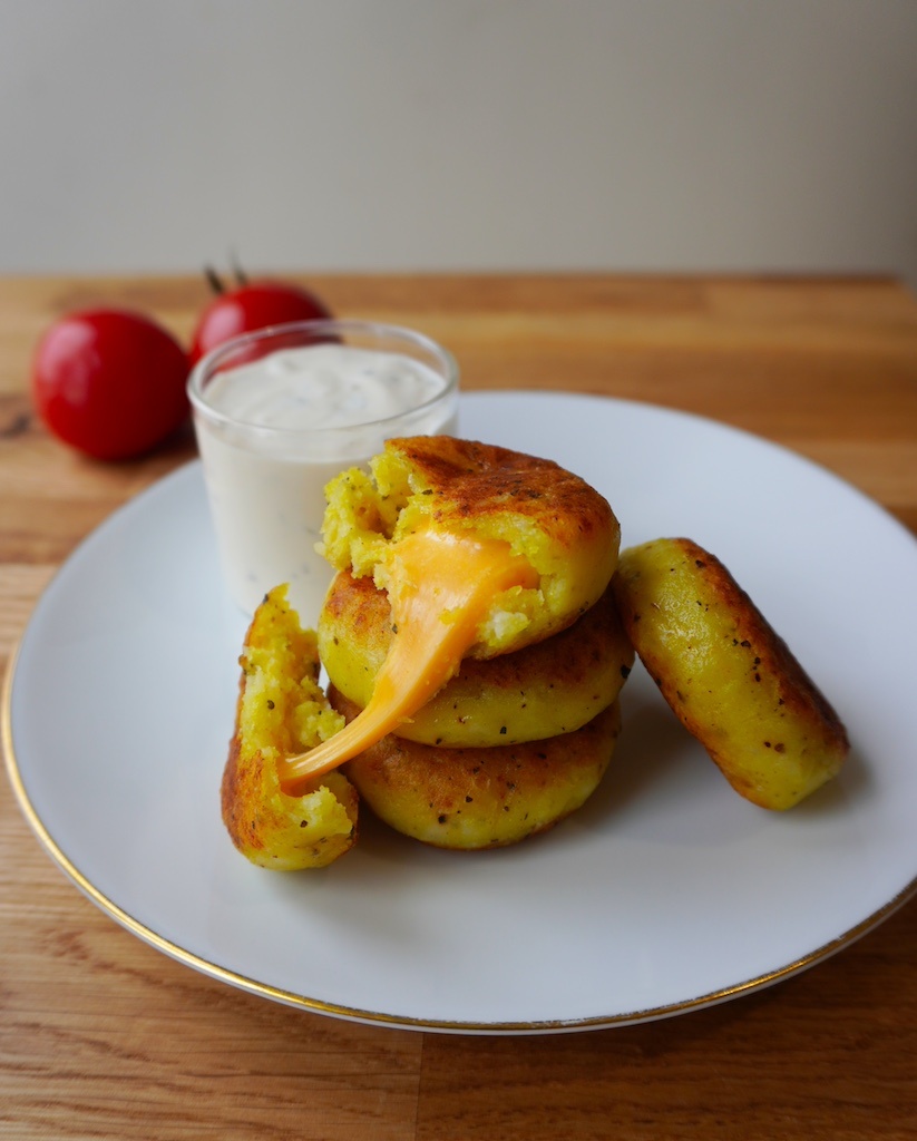 cheese stuffed potatoes in serving plate stacked up on each other one piece cut open with cheese melting out