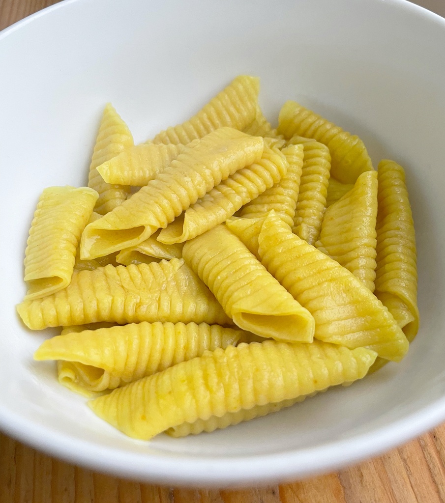 cooked garganelli pasta in white serving bowl