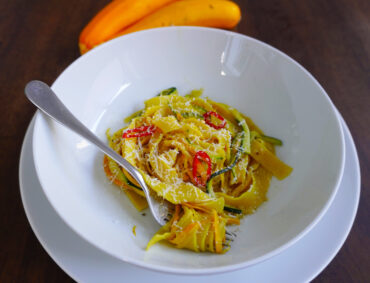 courgette pasta in pasta bowl hand-made pasta with spiralized yellow and green courgette and chilli sprinkled with grated parmesan
