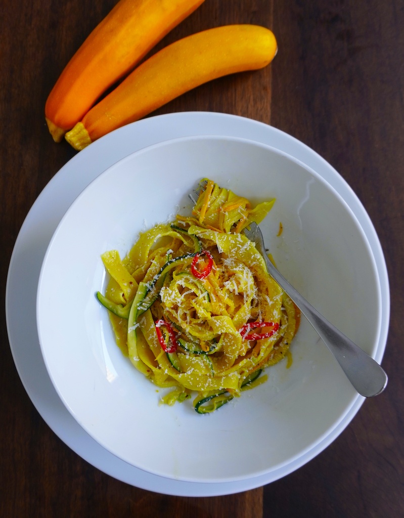 courgette pasta in pasta bowl hand-made pasta with spiralized yellow and green courgette and chilli sprinkled with grated parmesan flat lay