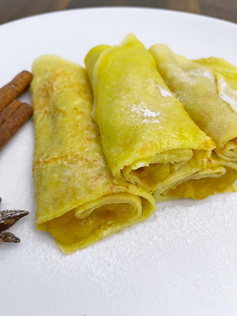 crepes with apple and walnut filling on the serving plate sprinkled with icing sugar