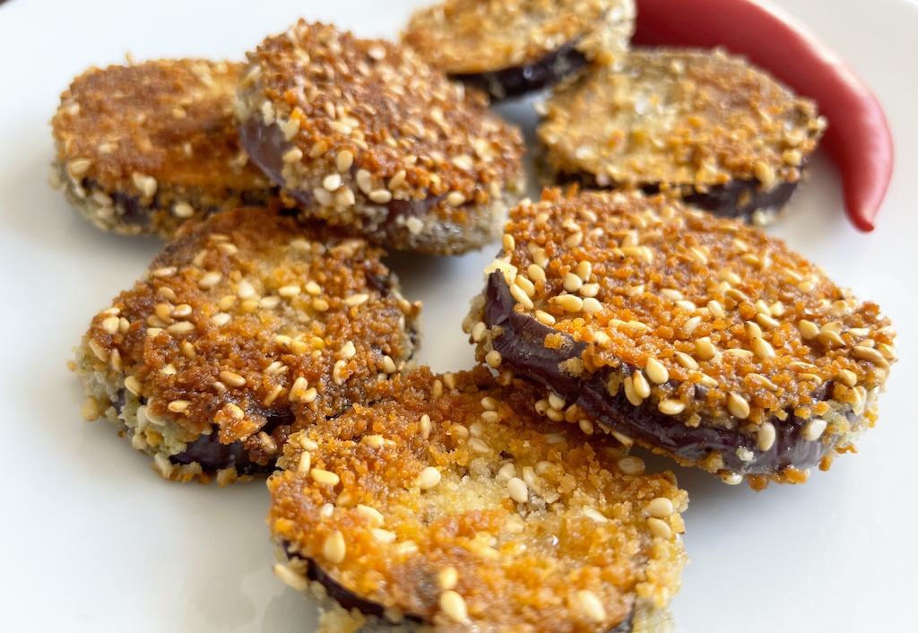 crispy fried aubergine on a plate with one slice in focus