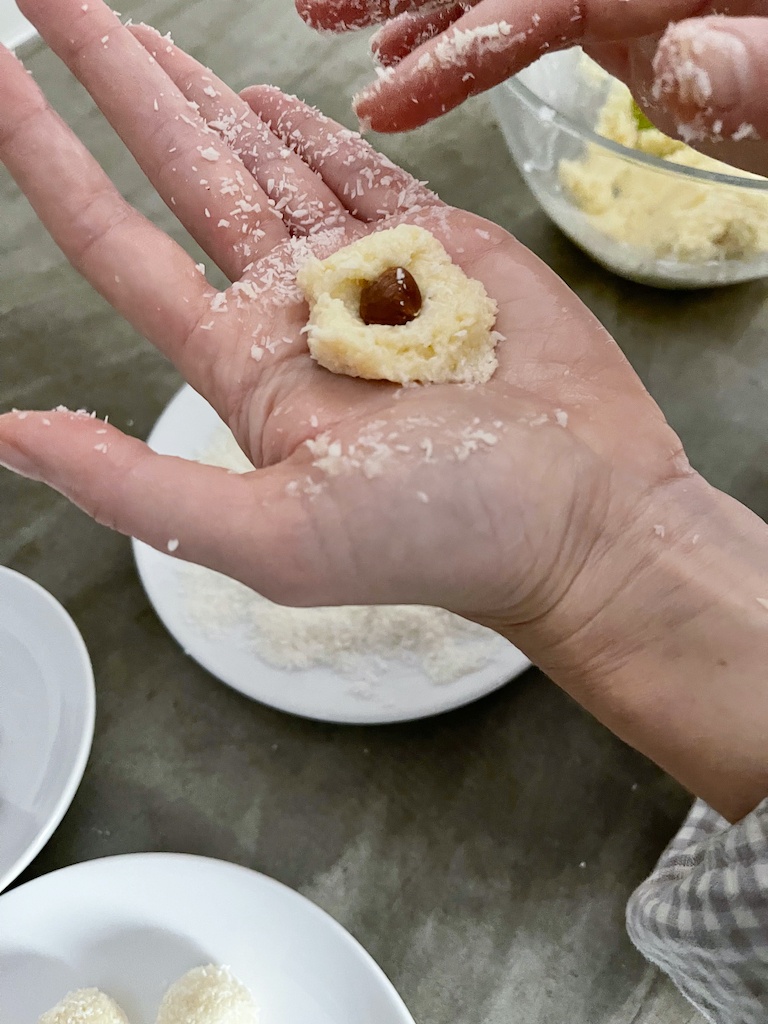 dough with hazelnut in hand while making coconut raffaello truffles