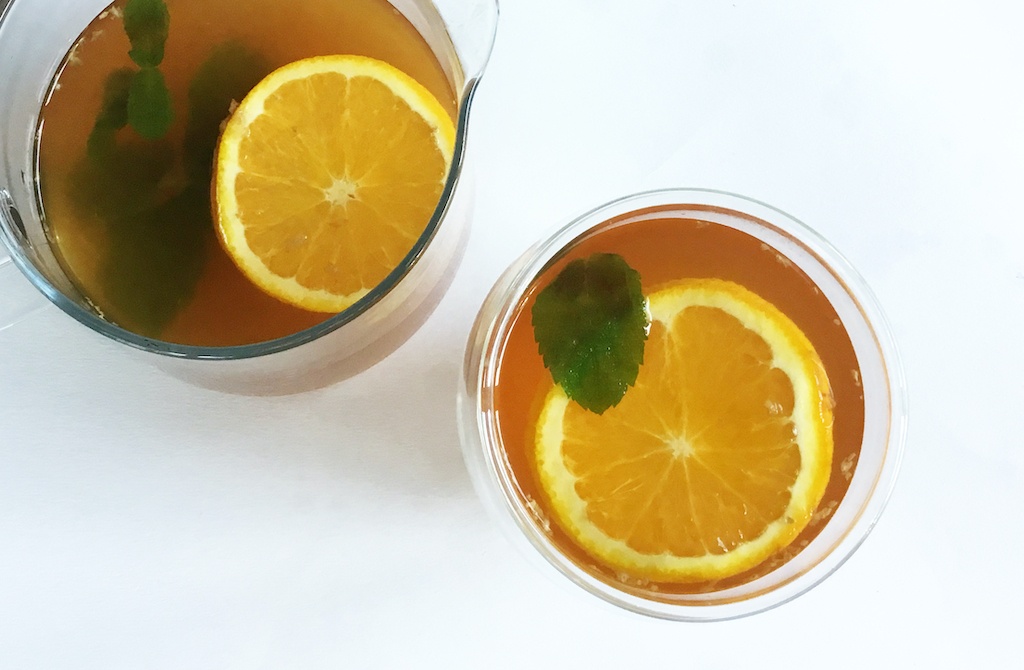 fresh orange and ginger tea in a glass and pot from the top