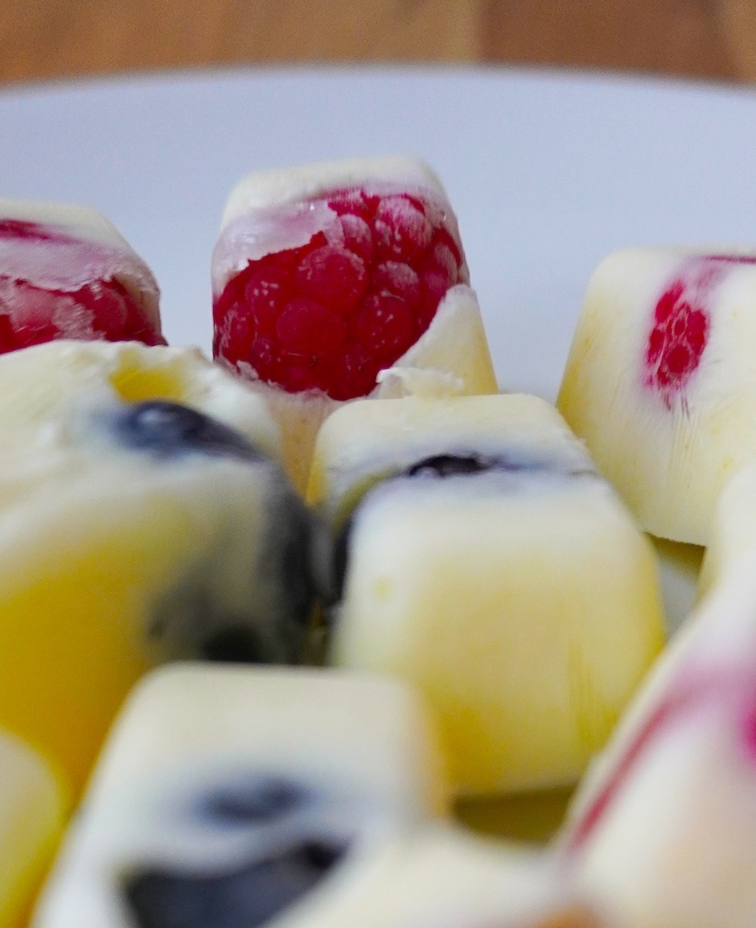 frozen yoghurt berry bites with close up on raspberry in background