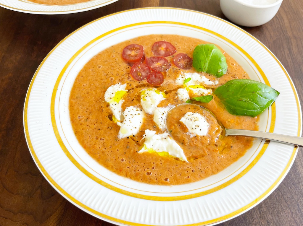 gazpacho with mozzarella and basil in a serving plate with a spoon