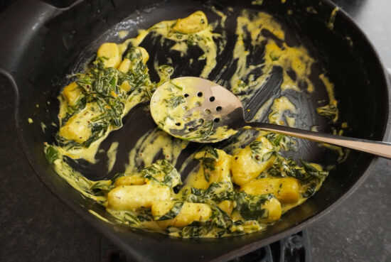 gnocchi with spinach and mascarpone - leftover gnocchi in cast iron frying pan with serving spoon in