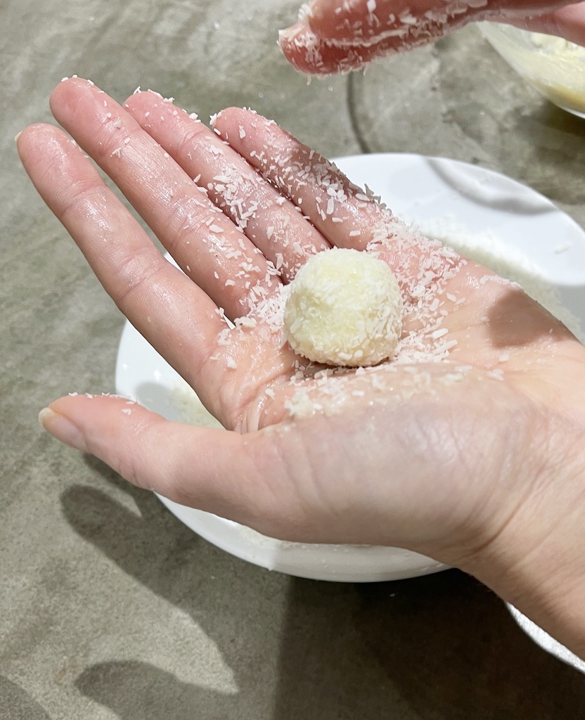 homemade coconut raffaello truffle in a hand after forming a ball