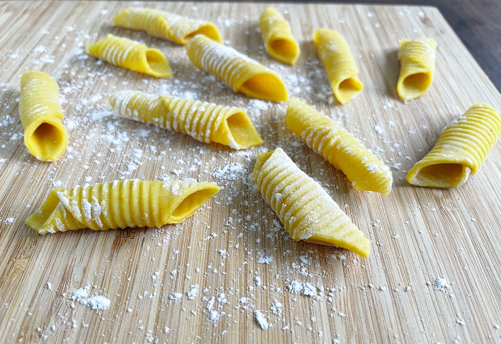 homemade garganelli pasta on wooden board - a close up