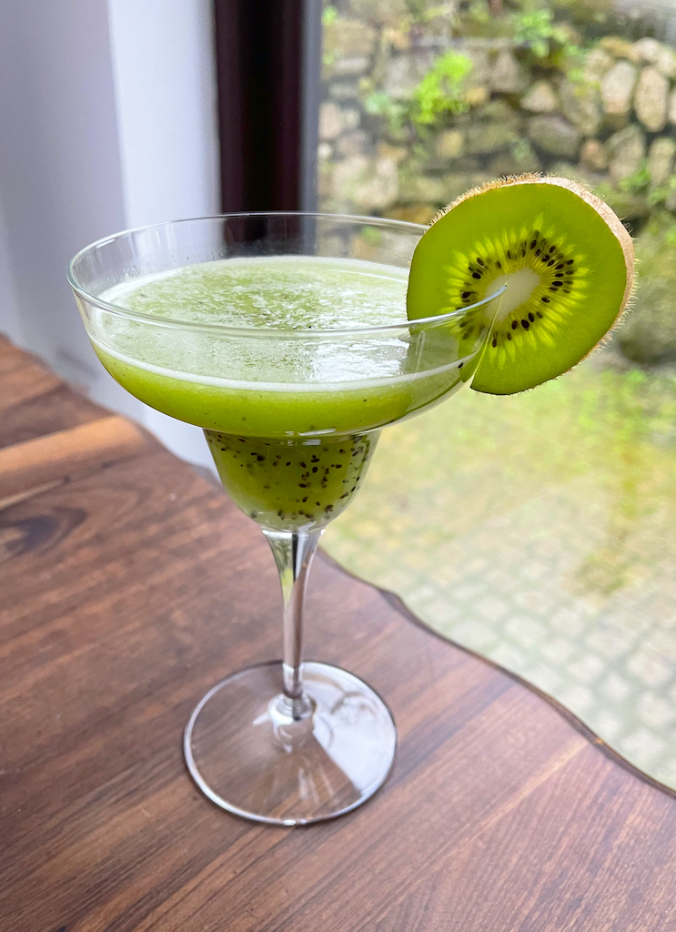 kiwi smash cocktail or mocktail in a glass with a window behind