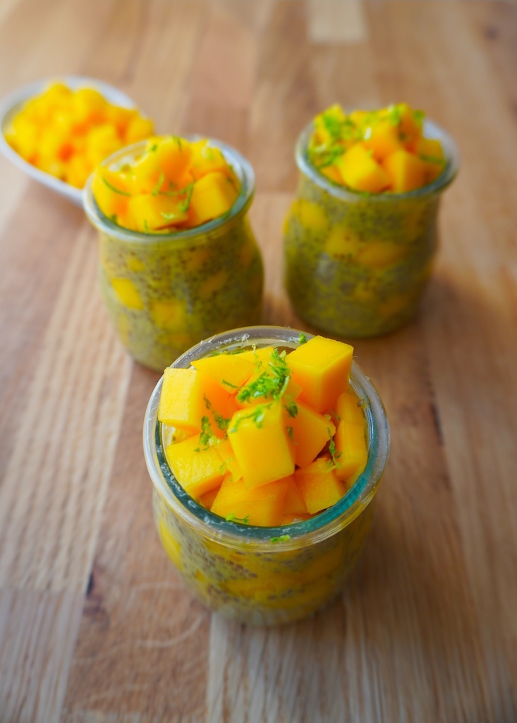 mango chia seeds pudding in glass containers on wooden worktop close up on mango pieces