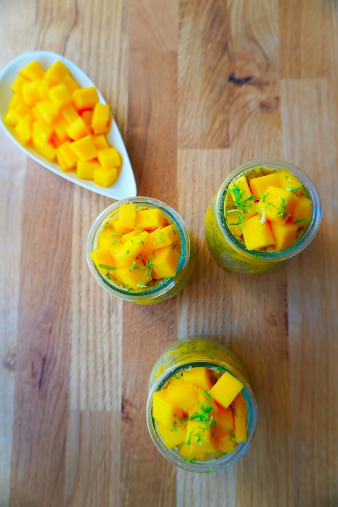 mango chia seeds pudding in glass containers on wooden worktop flat lay