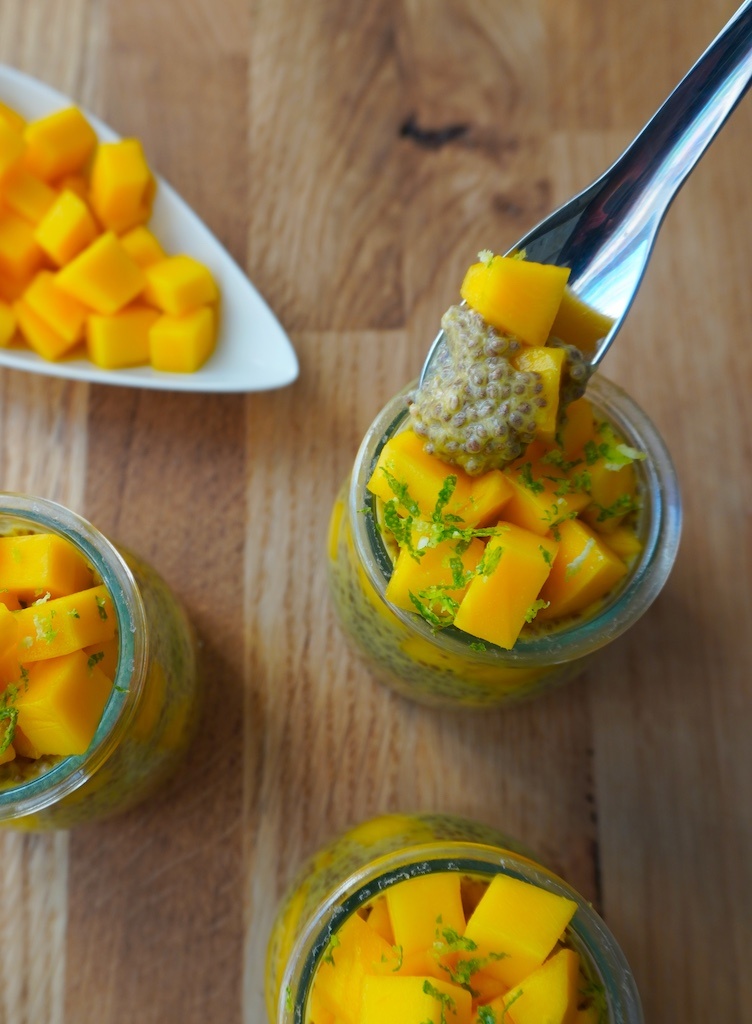 mango chia seeds pudding in glass containers with some pudding in spoon flat lay