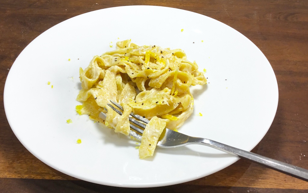 pappardelle with lemon peel on the plate with a fork