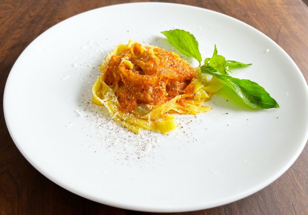 pappardelle with pepper and tomato sauce in serving plate on the table