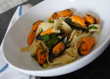 pasta with wine and garlic mussels in serving bowl close view from an angle