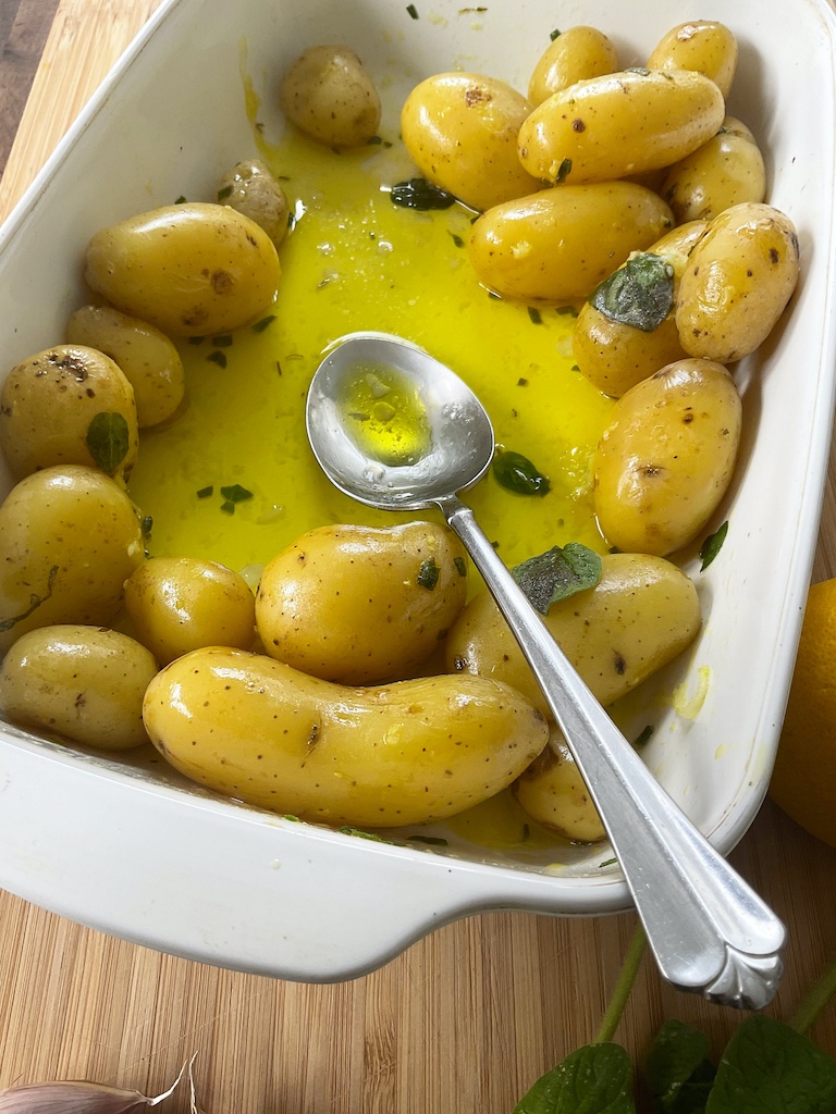 potatoes with salmoriglio sauce in a white dish and a serving spoon - a close up