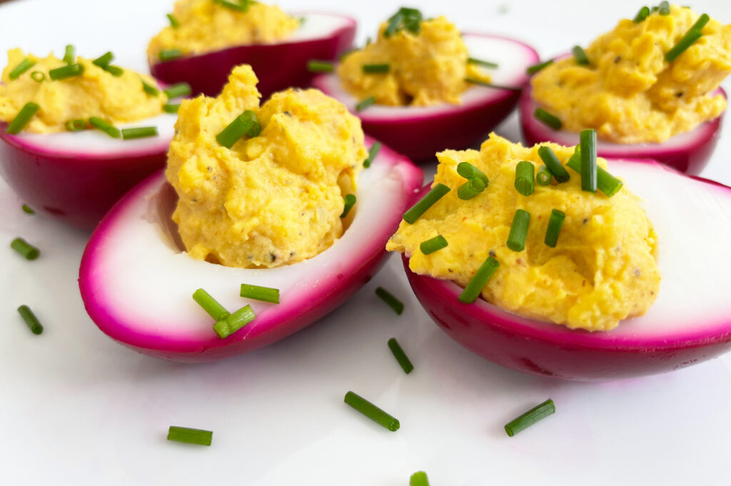 purple devilled eggs on a serving plate