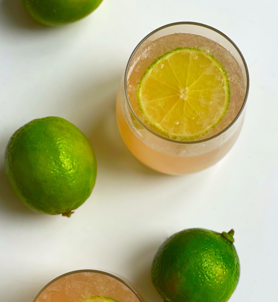 rhubarb tequila cocktail in a serving glass with limes around flat lay