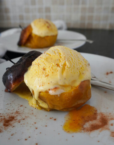 simply baked apples - two apples in serving plates with scoops of vanilla ice cream on top ice cream and apple juice melting and dripping onto plate