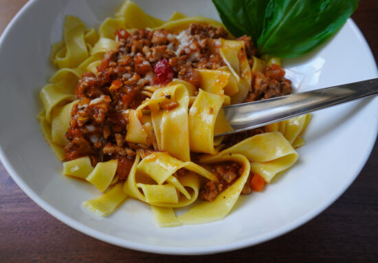 spaghetti bolognese in pasta bowl with fork with pasta wrapped around it