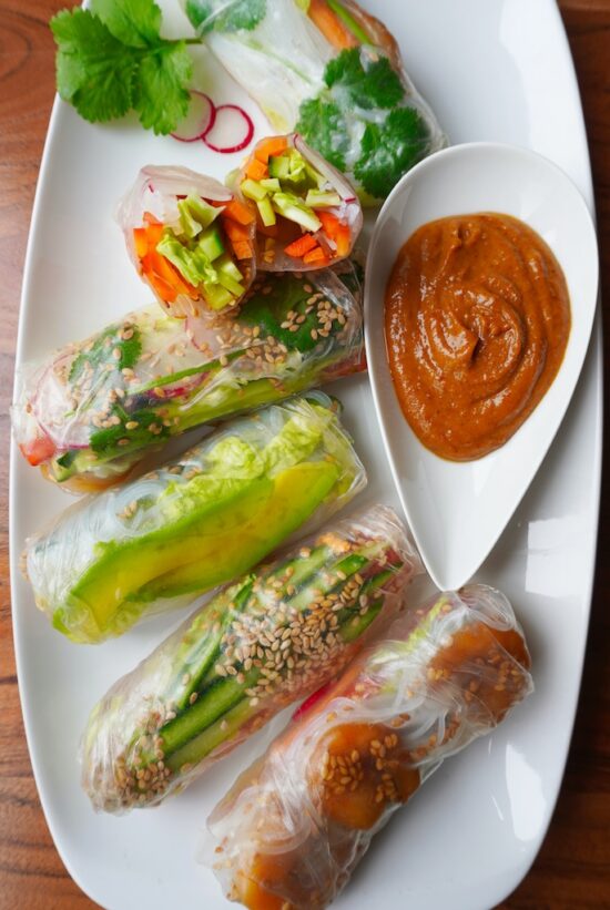 spring rolls in rectangular plate one roll cut through into halves to show the inside flat lay