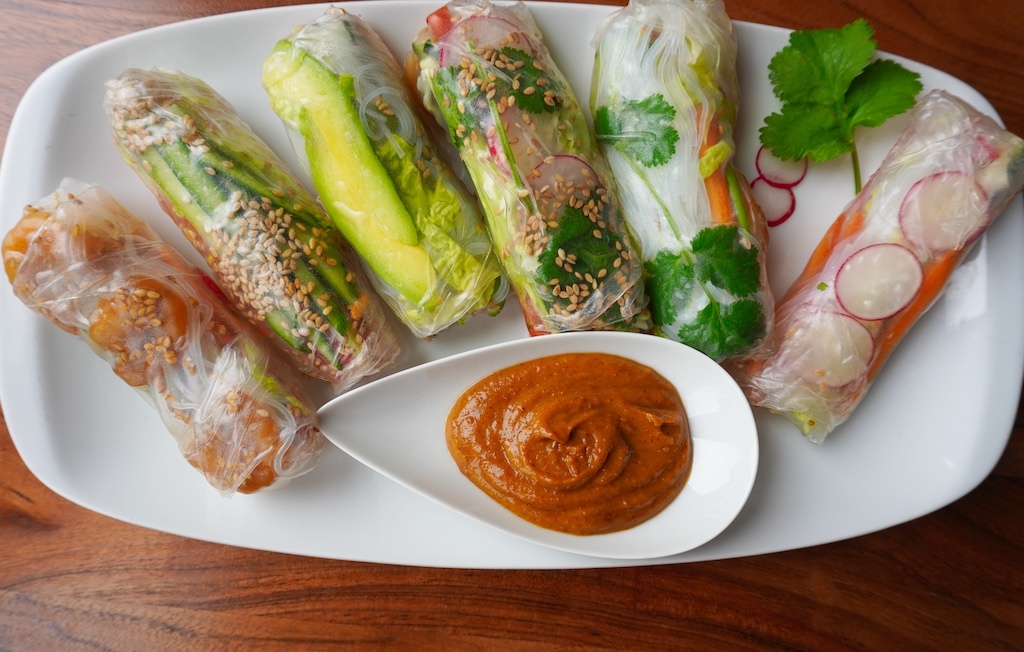 spring rolls in rectangular plate with peanut butter sauce in droplet shaped saucer horizontal view