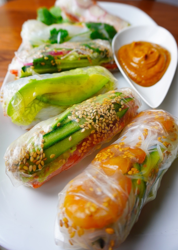 spring rolls in serving plat with peanut butter sauce in saucer close view