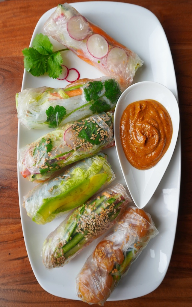 spring rolls on rectangular plate with peanut butter sauce in droplet shaped saucer flat lay