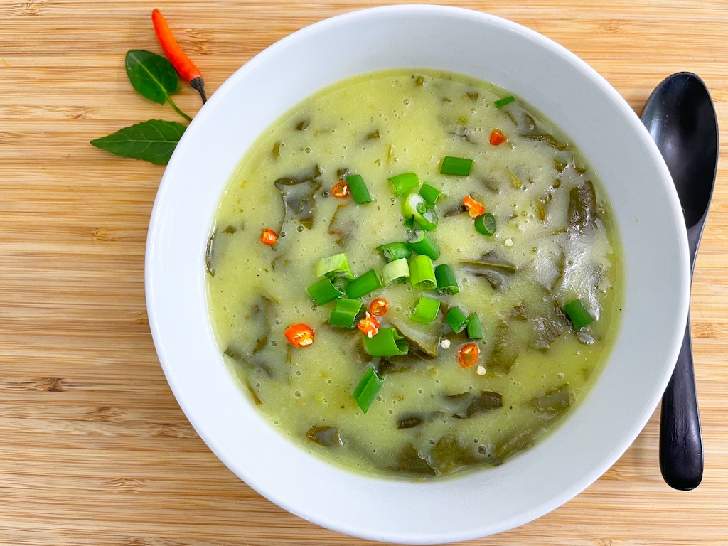 Thai style creamy sorrel soup - flat lay with a spoon and chilli and leaves decoration