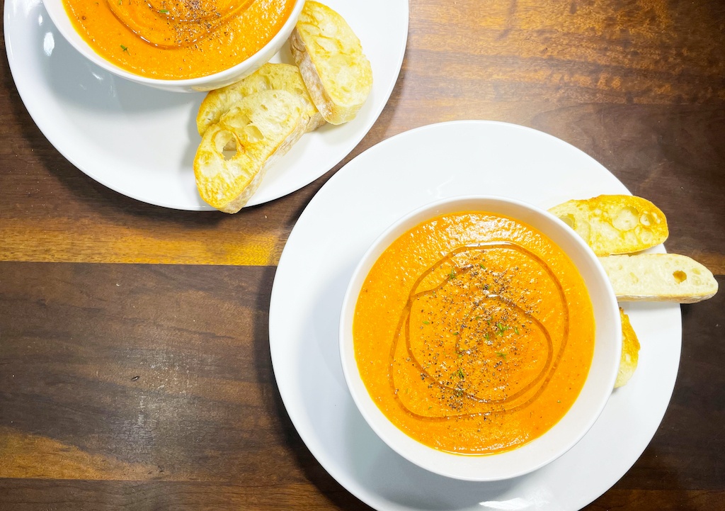 tomato white bean and garlic soup in two bowls on the table seen from above