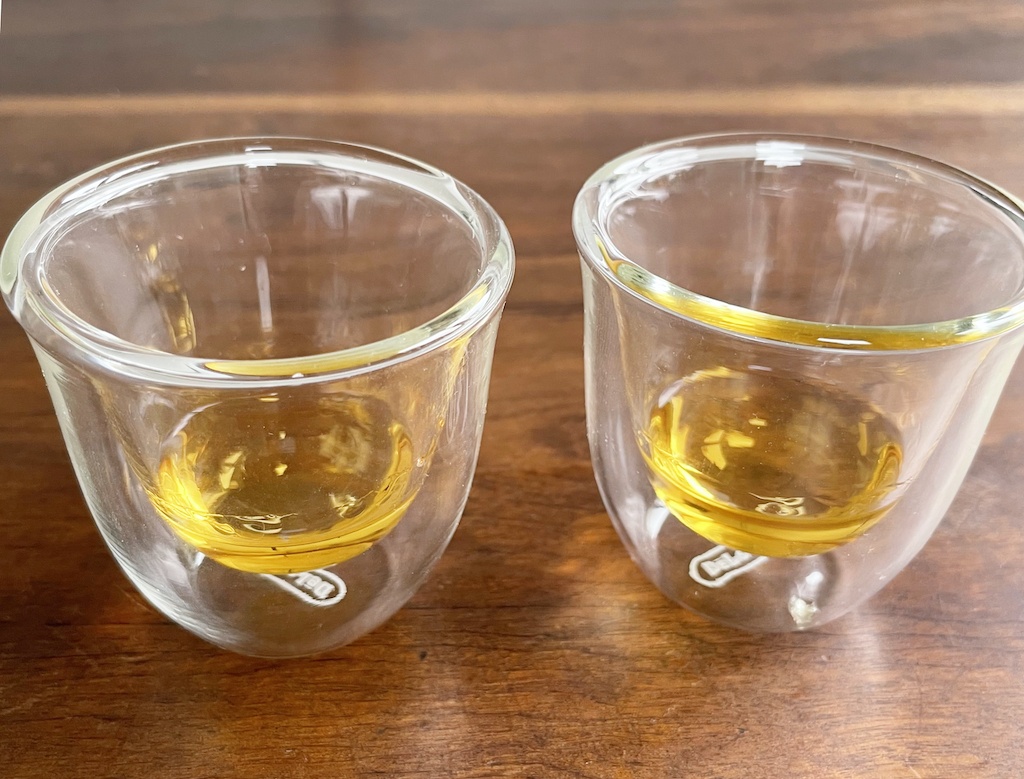 two small coffee cups with whiskey on the bottom