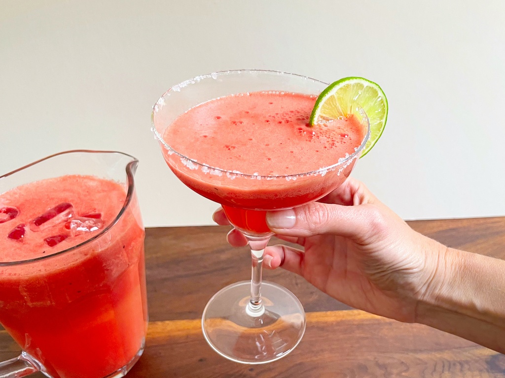 watermelon margarita in a hand in a serving glass