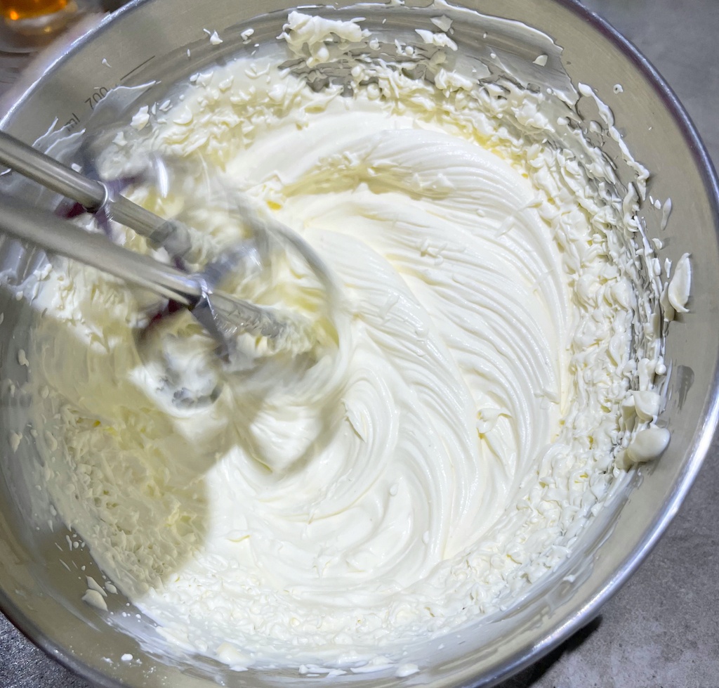 whipped cream in a metal bowl with an electric mixer