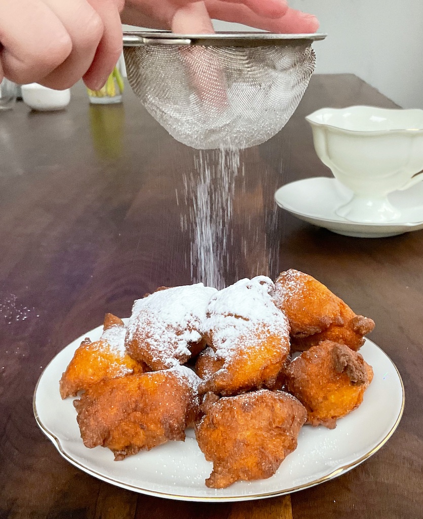 yoghurt doughnuts on the plate someone dusting them with icing sugar from tea strainer